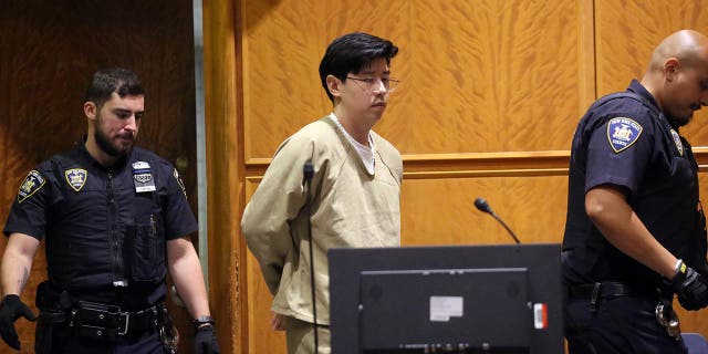 Alleged rapist doctor Zhi Alan Cheng in handcuffs is led into a courtroom