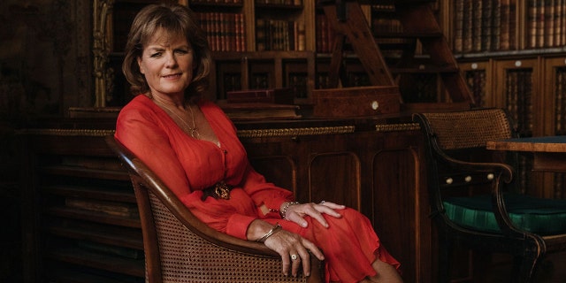 Emma, Duchess of Rutland wearing a red dress and sitting on a couch