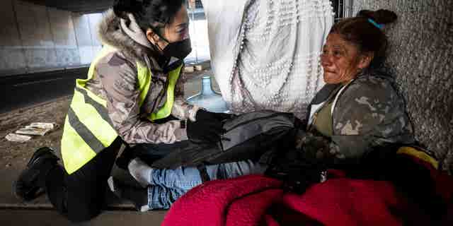 San Bernardino Mayor handing homeless woman under bridge a care package.