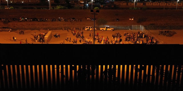 Crowds of migrants by Texas border wall