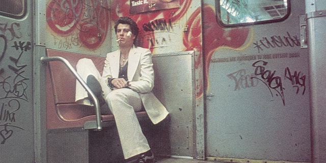 John Travolta sitting in a white suit in a scene from "Saturday Night Fever"