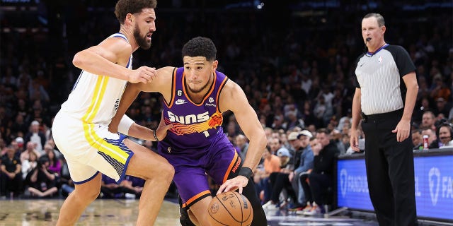Devin Booker drives against Klay Thompson