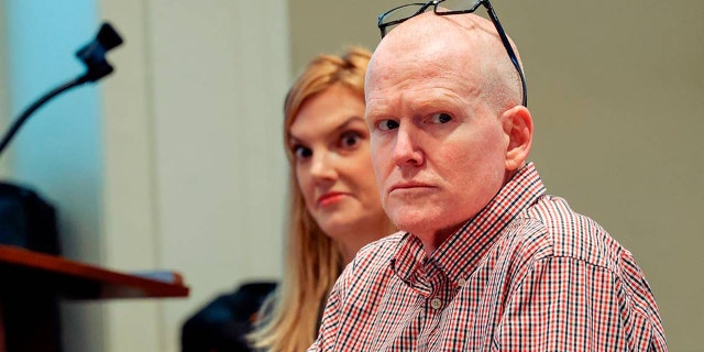 a close-up of the bald Alex Murdaugh in sitting in court with a plaid shirt next to his legal team