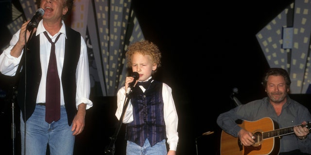 Art Garfunkel Jr. and his son on stage singing wearing identical outfits