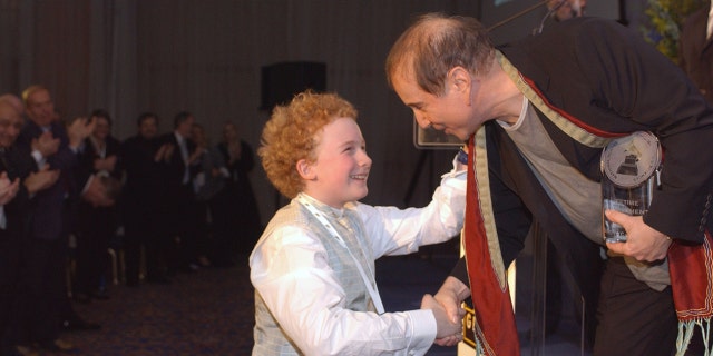 Paul Simon leaning down to Art Garfunkel Jr.
