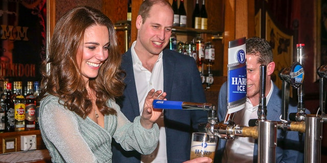 Kate Middleton wearing a pale green dress working the bar as prince william watches