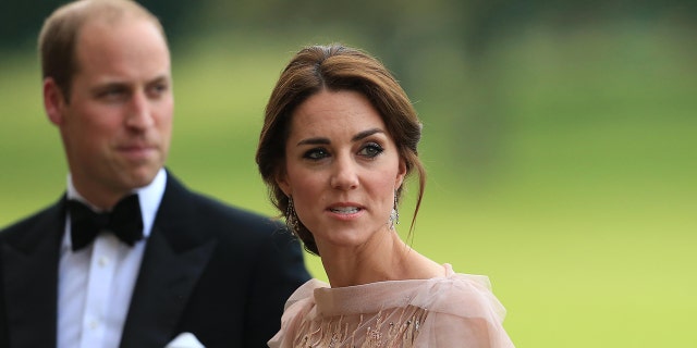 Kate Middleton wearing a pale pink dress next to Prince William in a tux