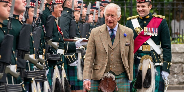 King Charles in traditional Scottish clothing being greeted by locals