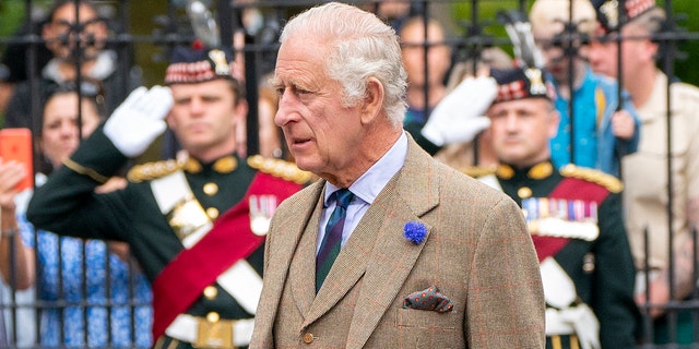 A close-up of King Charles in a brown suit