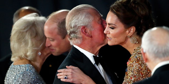 Kate Middleton in a gold gown being kissed on the cheek by King Charles