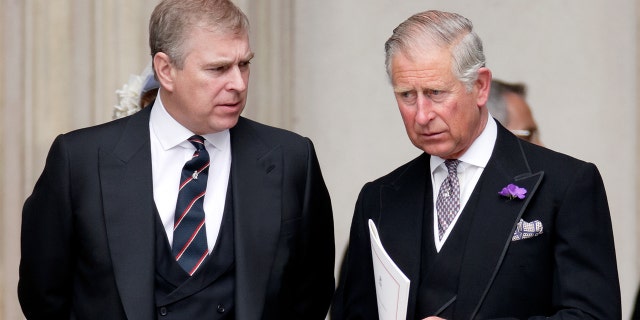 Prince Andrew and King Charles wearing matching dark suits looking serious