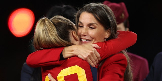 Queen Letizia hugging a football player wearing a red blazer