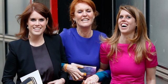Sarah Ferguson wearing a blue dress in the arms of her two daughters as they all laugh