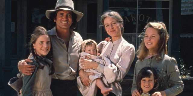 The cast of Little house in costume smiling and facing the camera