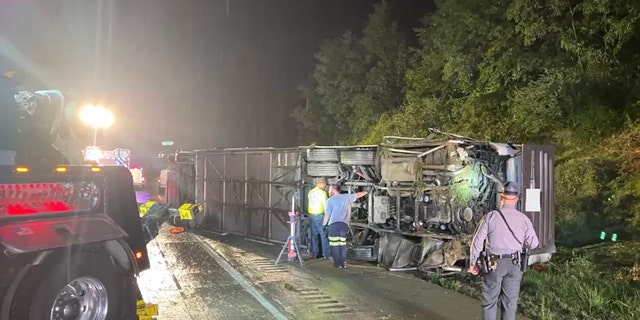 A bus on its side, people standing