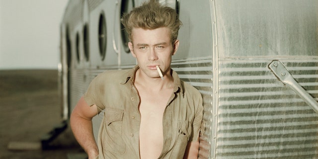 James Dean posing next to trailer with cigarette in his mouth