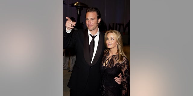 John Corbett pointing while posing next to Bo Derek