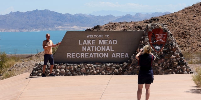 Tourists pose for photos at a sign for the Lake Mead National Recreation Area