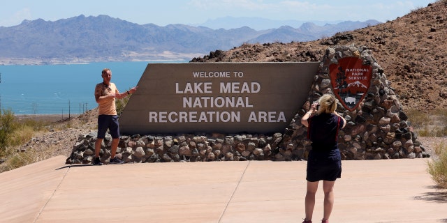 Tourists pose for photos at a sign for the Lake Mead National Recreation Area