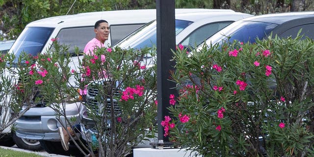man in pink shirt walks to car