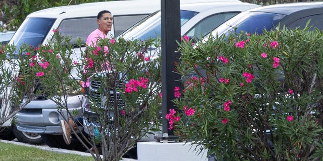 man in pink shirt walks to car