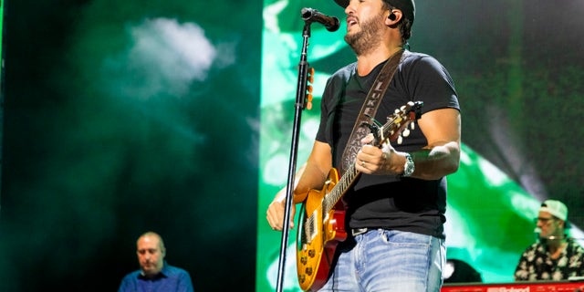 Luke Bryan singing on stage with guitar