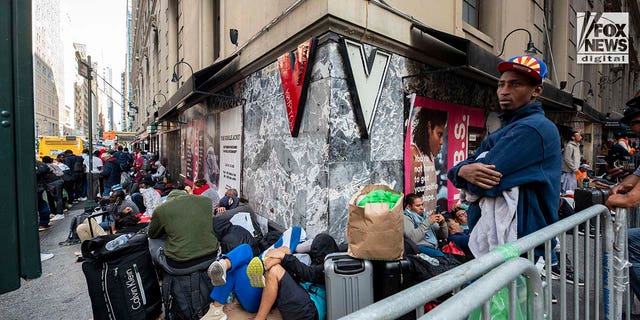 Migrants sit on the sidewalk in Manhattan