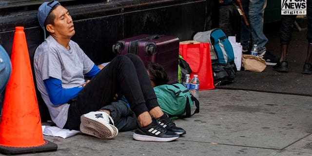 Migrant sitting on sidewalk outside hotel in NYC
