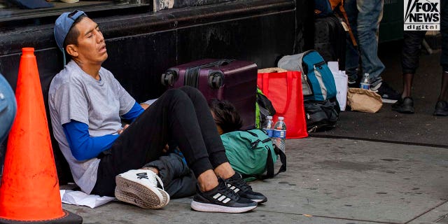 Migrant sitting on sidewalk outside hotel in NYC