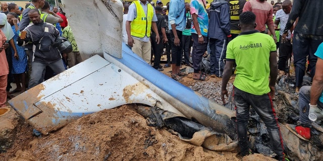 people standing by plane wreckage in Nigeria