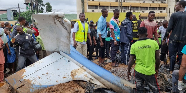 people standing by plane wreckage in Nigeria