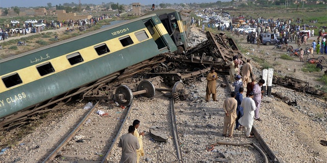 People looking at the derailed train cars in Pakistan