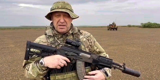 Prigozhin in military fatigues holding a weapon