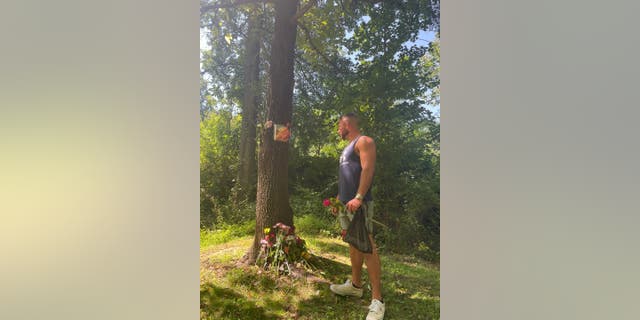 Richard Tobin stares at a tree trunk with a picture of Rachel Morin taped to it.