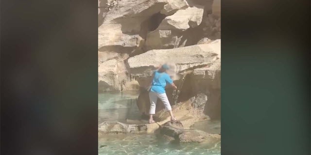 Woman fills water bottle at Trevi Fountain