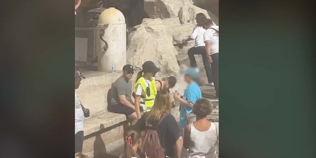 Security guard stops tourist at Trevi Fountain