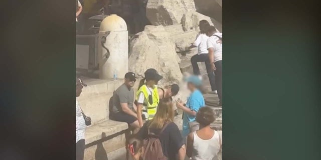 Security guard stops tourist at Trevi Fountain