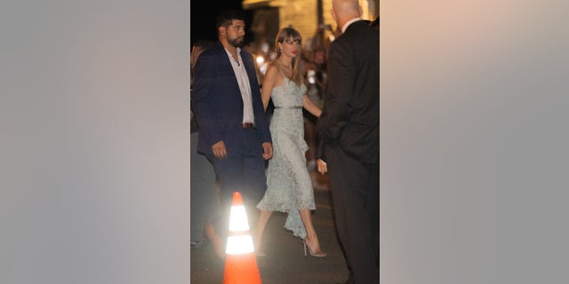 Taylor Swift walks with security in light blue lacy dress at rehearsal dinner