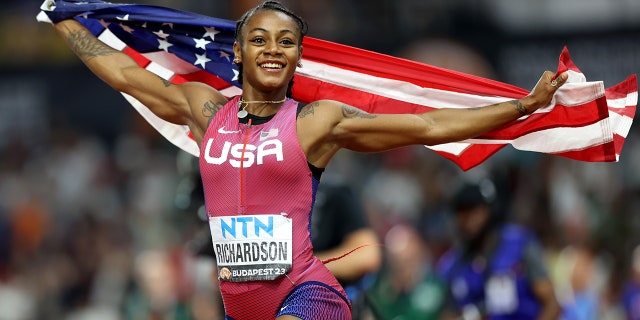 Sha'Carri Richardson holds up flag after winning race