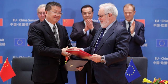 Chinese Minister of Energy Zhang Jianhua and European Climate Commissioner Miguel Arias Canete shake hands at a EU-China summit in Brussels on April 9, 2019.