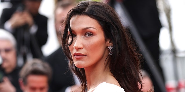 Bella Hadid in a white dress with a strand of hair in her right eye on the Cannes red carpet