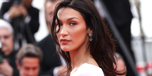 Bella Hadid in a white dress with a strand of hair in her right eye on the Cannes red carpet