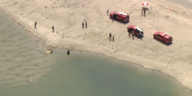 authorities at beach investigating barrel