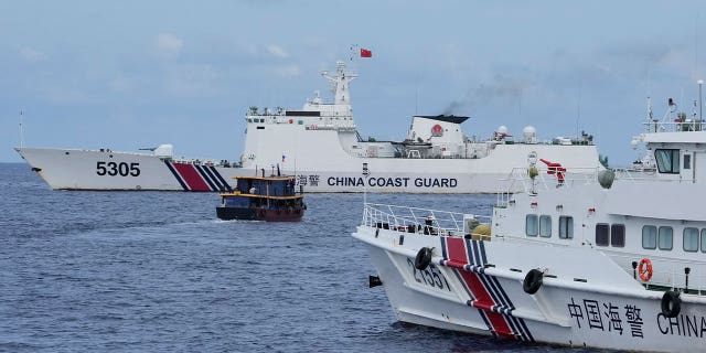 Filipino supply boat maneuvers around Chinese coast guard ships