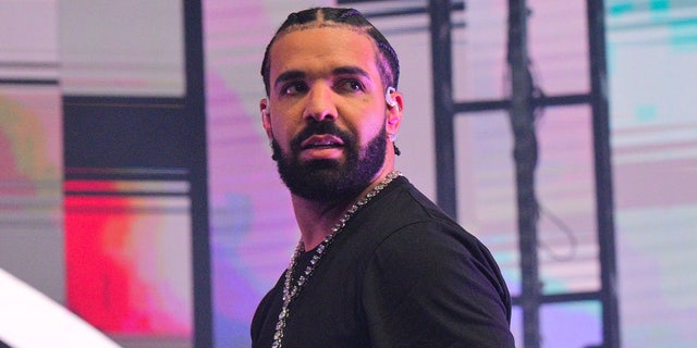 Drake looks back towards the crowd while performing in Atlanta in a black shirt