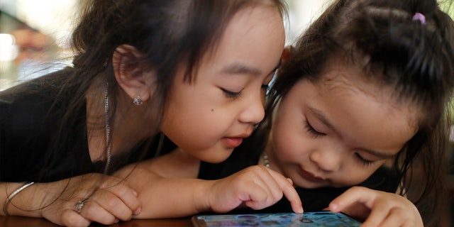 Two sisters playing on a smartphone.
