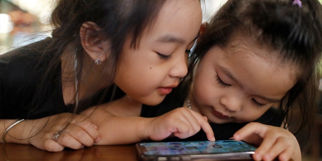 Two sisters playing on a smartphone.