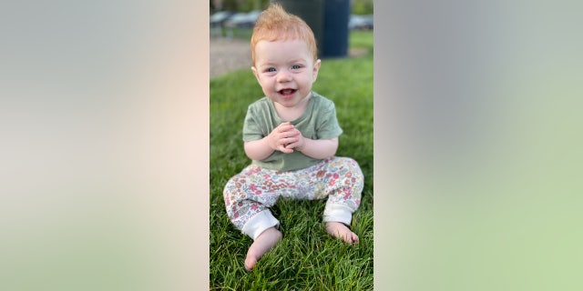 redheaded baby sitting in grass