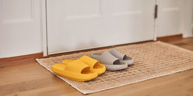 Slip-on sandals left on a floor mat near an entryway door.