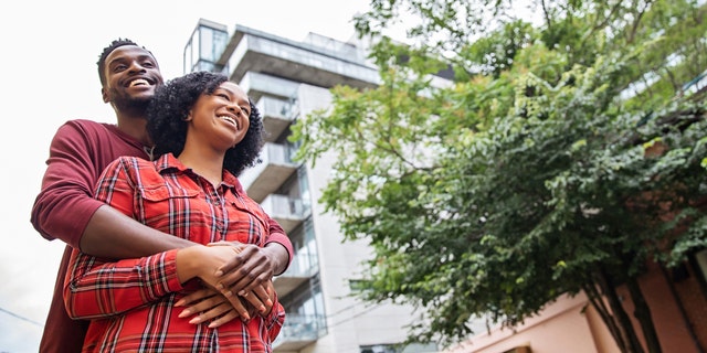 Tall man hugs his shorter female partner.